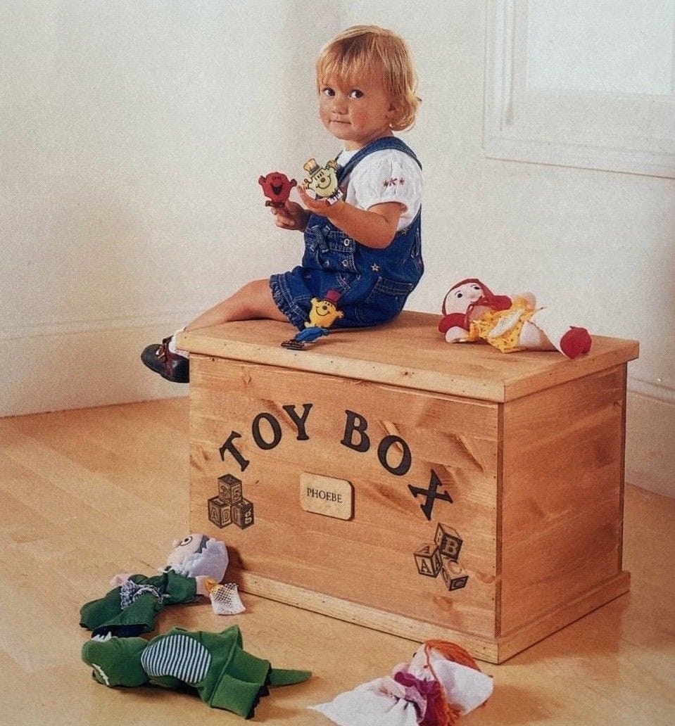 A young blonde Phoebe sat on her custom made toy box