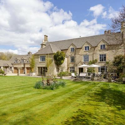 A large cotswolds country house with manicured gardens and lawn