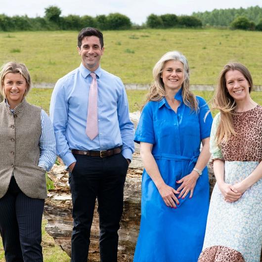Butler Sherborn stow team lean on a fallen tree in a grass pasture